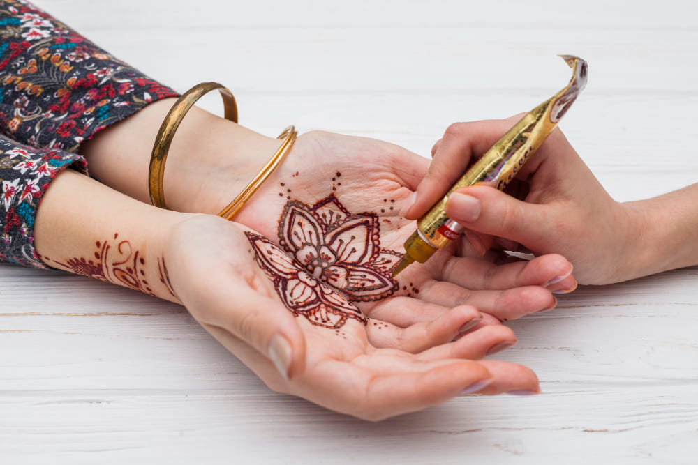 une fleur orientale dessiné au henné sur les paumes de main d'une femme